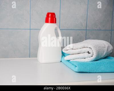 Flasche Reinigungsmittel und saubere Handtücher auf der Waschmaschine im Haus, Platz für Text. Wäscheservice Tag. Stockfoto