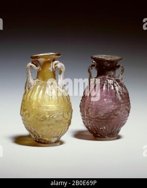 Diese Parfümflasche ist eines der ersten Beispiele für Glaswaren, die in eine Form geblasen wurden. Sie stammt vermutlich aus dem östlichen Teil des Mittelmeeres, wo auch die Technik des Blasformens erfunden wurde. In die große Hafenstadt Sidon werden solche Flaschen als "idonische Flaschen" bezeichnet. Die Flasche wird in eine Doppelform geblasen und ist mit einer Reihe zungenförmiger Elemente auf der Schulter und dem Fuß mit dazwischen liegenden Spiralen verziert. Die gelbe Farbe erhielt man durch den Zusatz von Silber. "Geschirr, Flasche, Glas, Gussform, 7,3 cm, Römerzeit 0-100 Anzeige, unbekannt Stockfoto