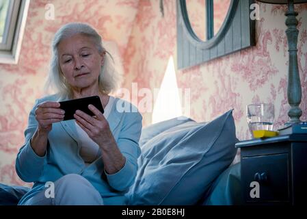 Ältere Frau beim Ansehen von Videos auf dem Smartphone Stockfoto