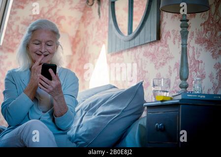Ältere Frau, die auf das Smartphone schaut Stockfoto