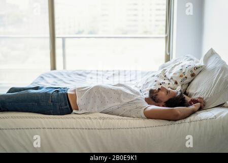 Junger Mann auf dem Bett liegend Stockfoto