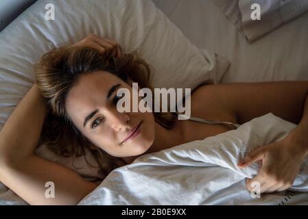 Junge Frau auf Bett liegend Stockfoto