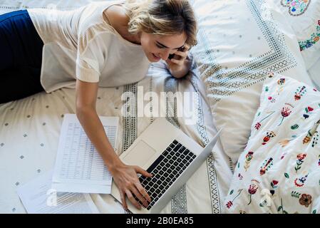 Frau mit Laptop am Bett Stockfoto
