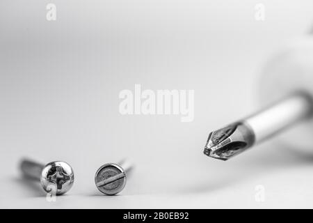 Nahaufnahme des Schraubendrehers sind Kreuz und verschiedene Schrauben. Werkzeuge. Kompatibilität. Repair. Kopierraum. Schwarzweißfotografie Stockfoto