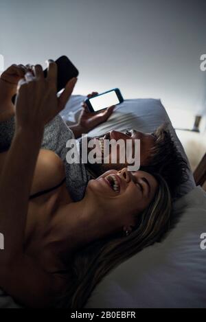 Fröhliches junges Paar mit Smartphones Stockfoto