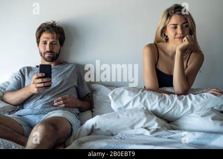 Junges Paar sitzt auf Bett Stockfoto