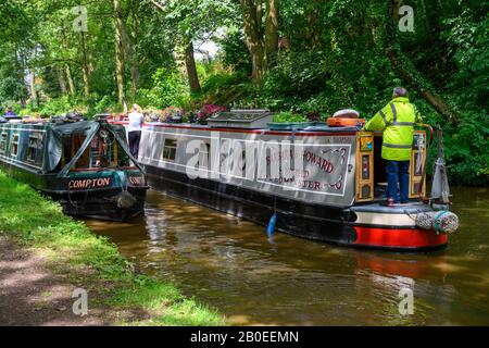 Der Mann auf einem schmalen Boot versucht, an einem vermoorten Boot auf dem Shropshire Union Canal bei Gnosall in Staffordshire vorbei zu manövrieren. Stockfoto