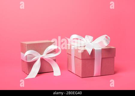 Trendige, attraktive, minimalistische Geschenke auf dem korallenroten Hintergrund. Tag der Frauen, Valentinstag, Alles Gute Zum Geburtstag und andere Feiertage. Stockfoto