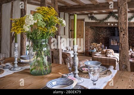 Schneiden Sie Blumen und große Kerzen auf dem alten Bauerntisch aus Kiefernholz Stockfoto