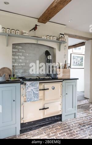 Hellblaue Einbauküche mit Kopfsteinpflasterboden Rayburn in Küche in Farrow & Ball's Matchstick mit original gepflastertem Boden. Stockfoto