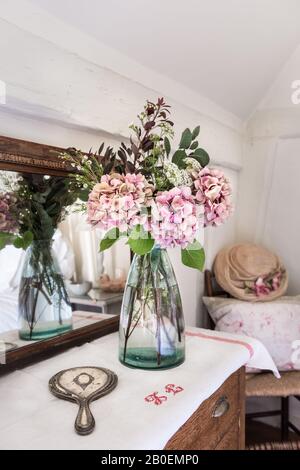 Pinke Hydrangeen mit Vintage-Handspiegel und Vase aus Garden Trading, die sich in einem antiken Spiegel widerspiegeln Stockfoto