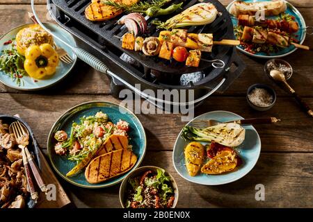 Vegetarisches und veganes BBQ Stillleben mit verschiedenen Bauernhof-frischen gegrillten Gemüse mit Tofu, Quinoa und Couscous auf einem alten rustikalen Tisch im Freien Stockfoto