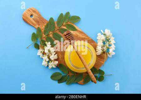 Honig im Glas und akazie Blüten auf blauem Hintergrund, Ansicht von oben Stockfoto