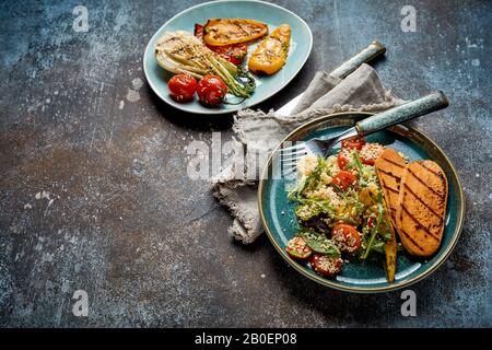 Zwei Teller leckeres gegrilltes frisches gemischtes Gemüse direkt vom Grill auf einem rustikalen grau strukturierten Hintergrund mit Kopienbereich Stockfoto