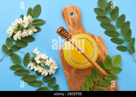 Honig im Glas und akazie Blüten auf blauem Hintergrund, Ansicht von oben Stockfoto