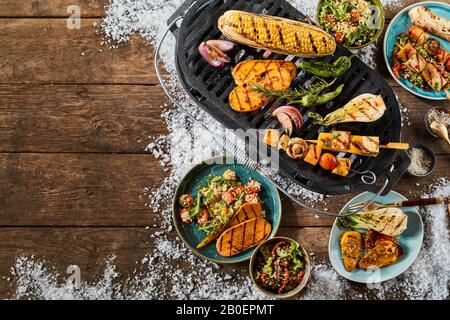 Köstliches Sortiment an vegetarischen Grillspeisen mit einer Auswahl an frischen Gemüse auf dem Bauernhof, Quinoa, Couscous und Tofu auf einem rustikalen Tisch mit Winterschnee a Stockfoto