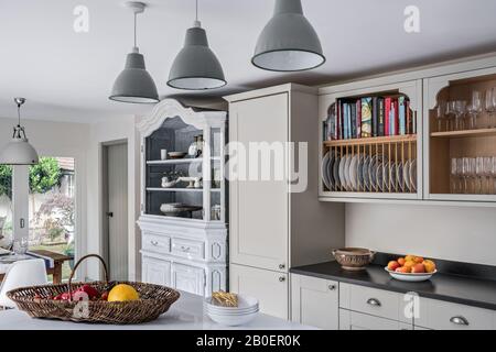 Belgische Oak Armoire aus den vierziger Jahren mit lackierten Lampenschirmen aus Amiens in Quäker-Küche mit Plattengestell über Granit Arbeitsplatte. Stockfoto