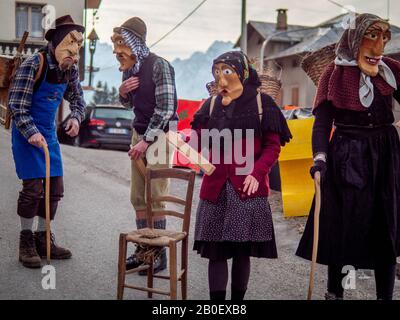 Die Menschen tragen Masken während des Karnevals in Dosoledo.Karneval in Dosoledo in Comelico ist eine Flamme von Farben, Blumen, Holzmasken und traditionellen Figuren. Stockfoto