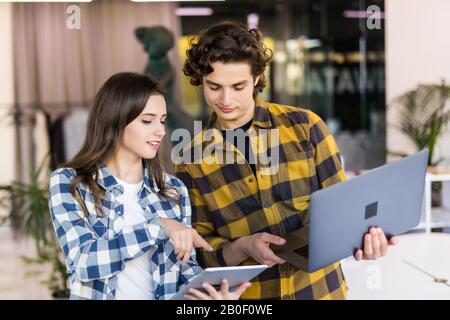 Aufnahme von zwei Designern, die in ihrem Büro arbeiten und dabei etwas auf ihrem Laptop zeigen. Stockfoto