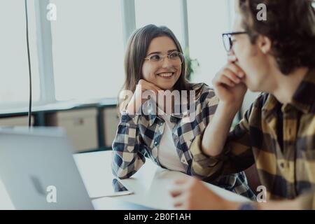 Schöne junge Business Partner sind ein Laptop verwenden, um Dokumente und lächelnd, während im Büro arbeiten Stockfoto