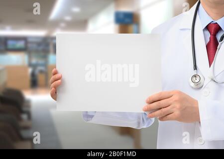 Ein männlicher Arzt, der eine Meldungsplatine in einem Krankenhaus hält. Stockfoto