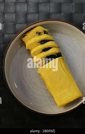 Hauskoch Japnese Eieromelett "Tamagoyaki" Rolle mit Spinat. Stockfoto