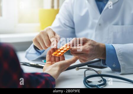 Arzt berät weibliche Patientin über Pillen. Arzt verschreibt Medikamente am Schreibtisch im Klinikum Stockfoto