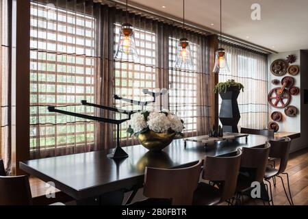 Hängeleuchten aus Glas über dem Esstisch mit Hydrangea in Kupfervase Stockfoto