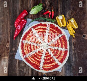 Nahaufnahme der italienischen Pizzazubereitung. Tomatensauce auf Pizzateig verteilen und mit anderen Zutaten backen. Stockfoto