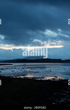 Sonnenuntergang über der Ardmaddy Bay, Schottland am Weihnachtstag, während die letzten Sonnenstrahlen auf das Wasser fallen, was eine Goldspiegelung gegen die Dunkelheit liefert Stockfoto