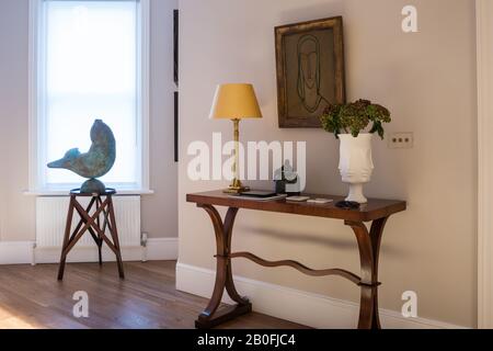 Eleganter Saal mit Wellen-Trage-Tisch, von Soane Britain und bronzener Fischskulptur nach Willy-Kreitz. Stockfoto
