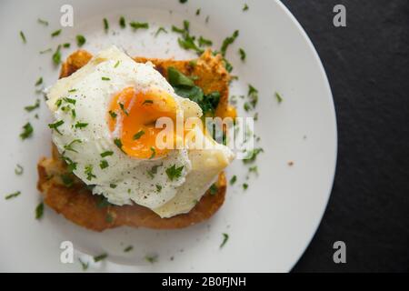 Ein pochiertes Ei, das auf einem geräucherten, ungefärbten Haddockfilet serviert wird, Melanogrammus aeglefinus, das von einer Fischtheke im Supermarkt in Großbritannien gekauft wurde. Das Gericht Stockfoto