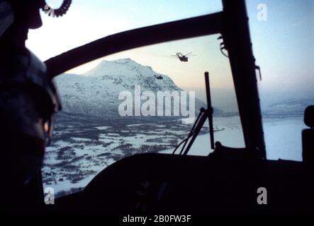 Puma-Hubschrauber der Royal Air Force der RAF fliegen in der Dämmerung während einer NATO-Übung in der Nähe von Tromso, Norwegen 1979, über Berge. Stockfoto