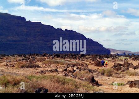 Menschen, die über felsige Vorlandshore in Richtung Meer bei Orzola, Lanzarote, Kanarischen Inseln, Spanien laufen Stockfoto