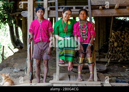 Herr Munney (Der Dorfjäger) Von Der ethnischen Gruppe Kayaw Posiert Mit Seiner Frau und EINEM Tourführer, Htay Kho Village, Loikaw, Myanmar, Außerhalb Seines Hauses. Stockfoto