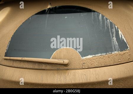 Das Detail der Heckscheibe eines Autos, komplett mit Schlamm bedeckt. Das ganze Auto ist verschmutzt und muss präzise gereinigt werden. Stockfoto