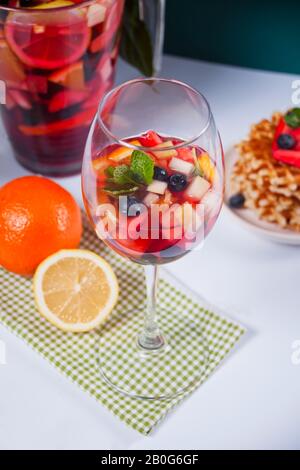 Rotwein frischer Sangria oder Stanzen mit Früchten, Minzblättern und Beeren. Hausgemachte Waffeln im Hintergrund Stockfoto