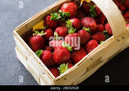 Frische reife Erdbeeren in einem Holz- Korb auf einem dunklen Hintergrund. Organische saftige Beeren. Ansicht von oben. Kopieren Sie Platz für Ihren Text. Stockfoto