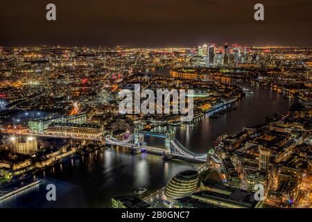Luftaufnahme der Tower Bridge und London nach Einbruch der Dunkelheit mit canary Wharf und der Stadt entlang der Themse Stockfoto