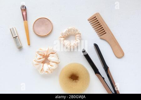 Haarbürste aus Holz, Haarglätter und Seide aus Gelb auf Weiß isoliert. Flat Lay Frisierwerkzeuge und Accessoires Color Hair Scrunchies Stockfoto