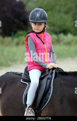 Junges Mädchen lernt, ein Pferd zu reiten Stockfoto