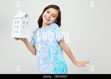 Lächelndes Teenager-Mädchen mit einem Mock zu Hause auf weißem Hintergrund mit Kopierraum. Unbewegliches Eigentum Stockfoto