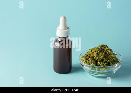 Glasflasche mit CBD- oder THC-Öl mit Hemp- oder Cannabis-Knospen Isoliert auf Aqua Blue Hintergrund mit Copy Space Stockfoto