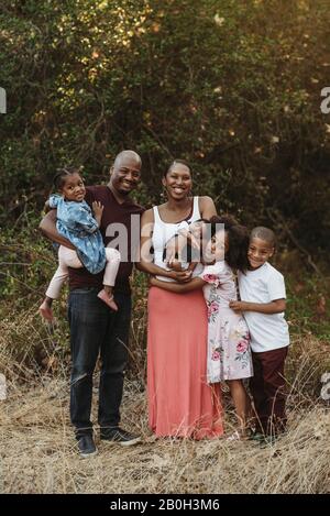 Porträt der jungen Familie und drei Mädchen im Feld stehen Stockfoto