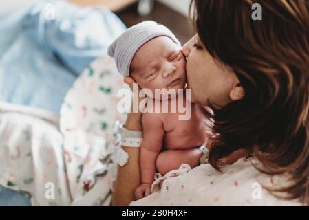 Nahaufnahme Detail der Mutter küsst neugeborenen Sohn die Wange im Krankenhaus Stockfoto