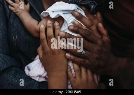 Nahaufnahme der Hände der Familie, die alle das Neugeborene halten Stockfoto