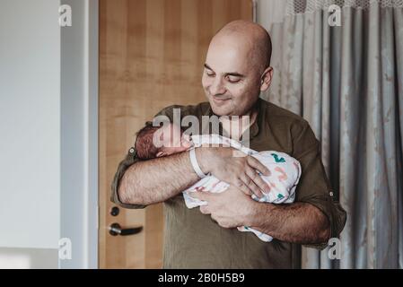 Glücklicher Vater hält neugeborenen Jungen in Decken im Krankenhaus eingewickelt Stockfoto