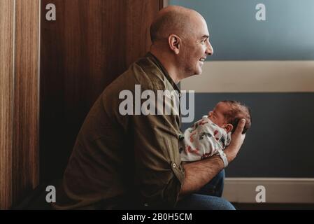 Seitenansicht des glücklichen Vaters, der neugeborenen Sohn im Krankenhaus hält Stockfoto