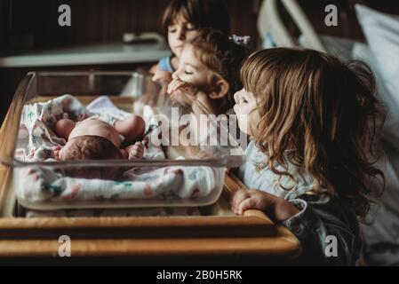 Drei Geschwister, die einen neugeborenen Bruder im Krankenwagen angucke Stockfoto