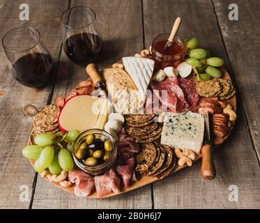 Nahaufnahme von Charcuterie-Tafel und Gläsern Wein auf Holztisch. Stockfoto